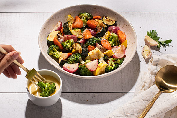 bowl of roasted vegetables with dipping sauce alongside