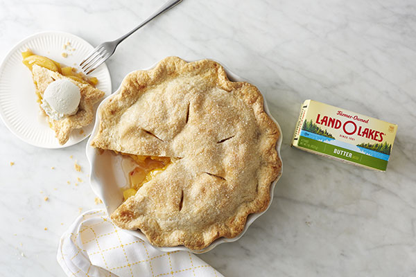 peach pie with ice cream-topped slice on plate, butter box alongside