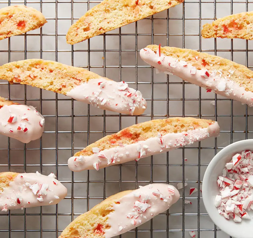 overhead shot of biscotti on cooling rack, small bowl of crushed candy canes alongside