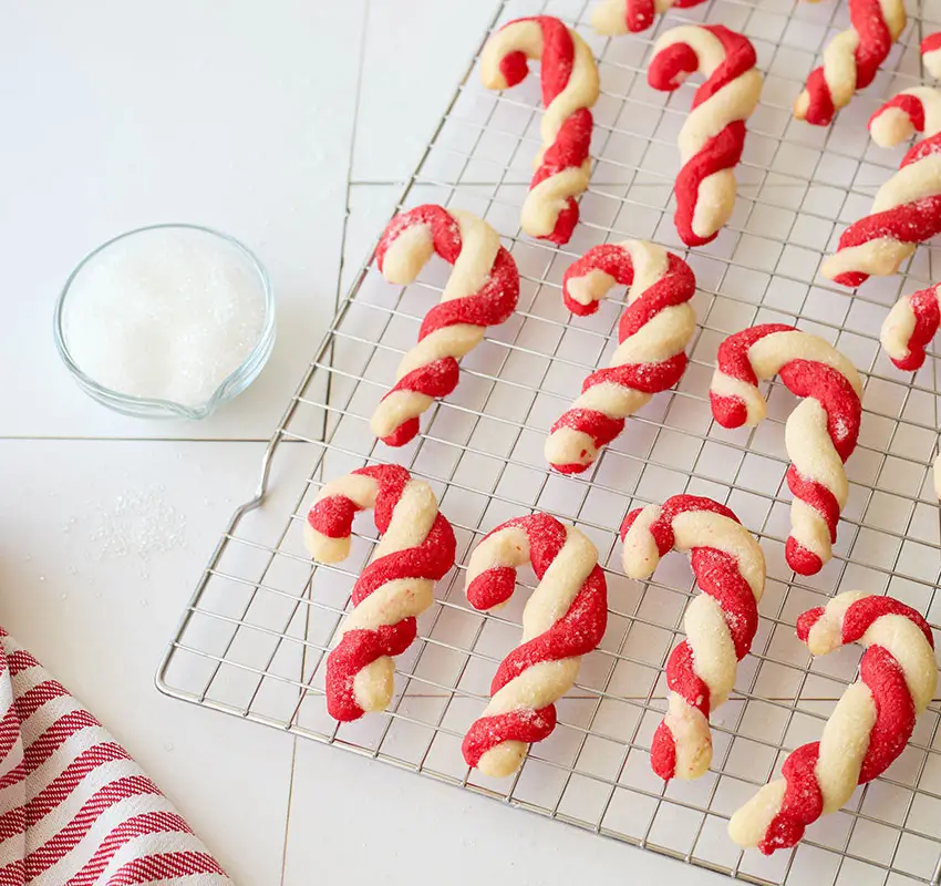 candy cane twist cookies on cooling rack, red and white striped towel in lower left corner